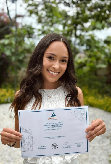 Jane smiling and holding her yoga teacher training certificate